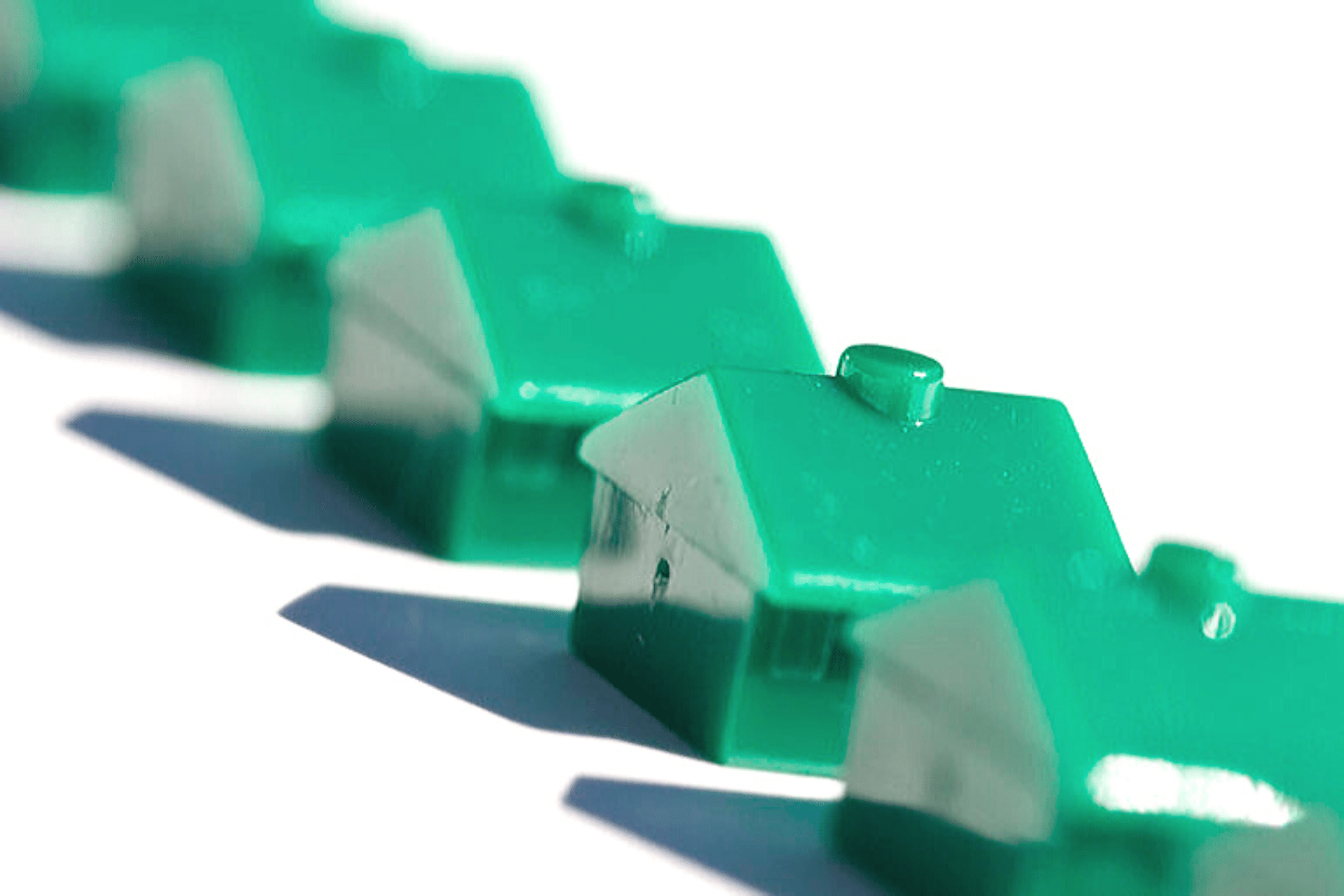 A row of three tiny green toy houses.
