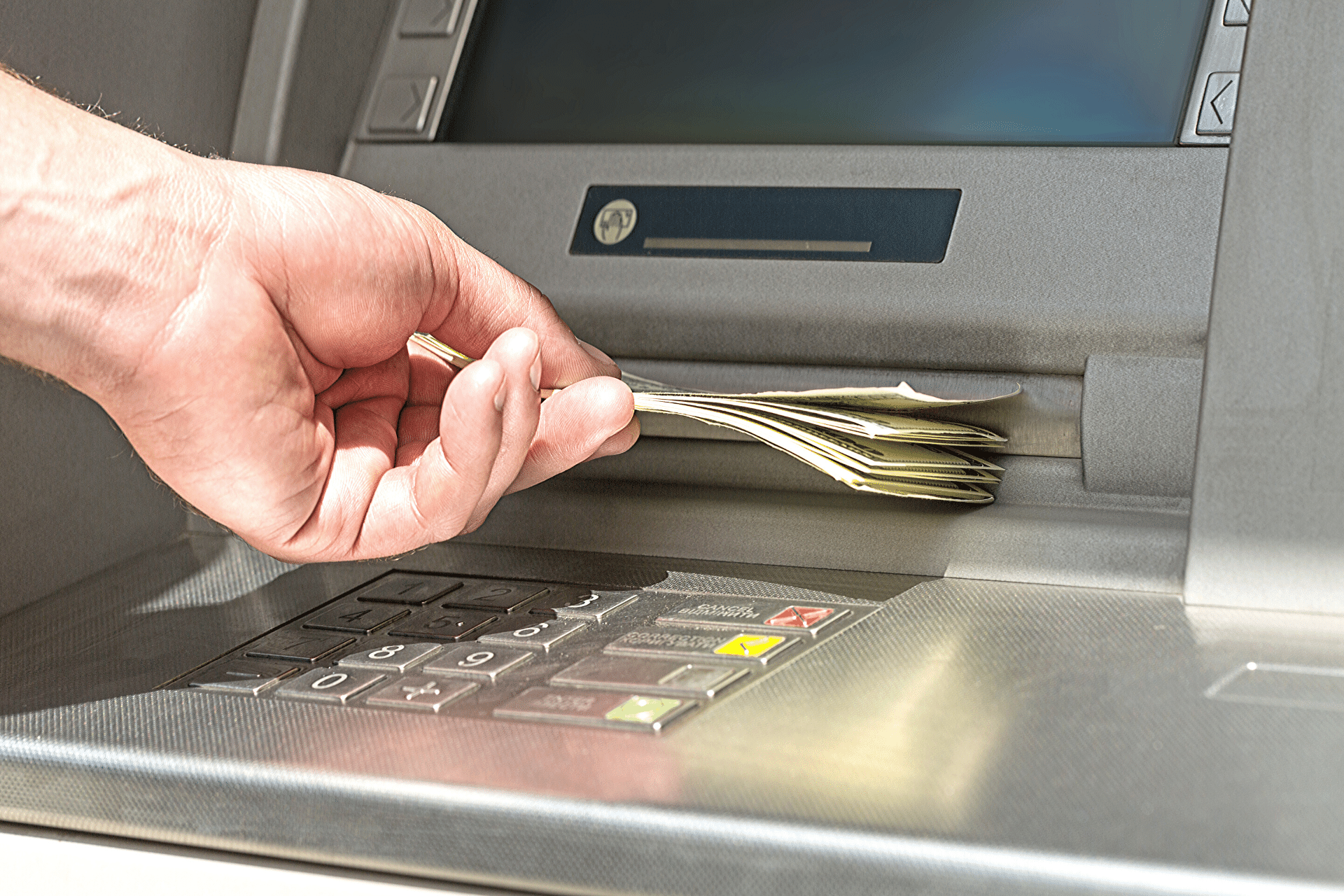 A hand pulling out money from an atm machine