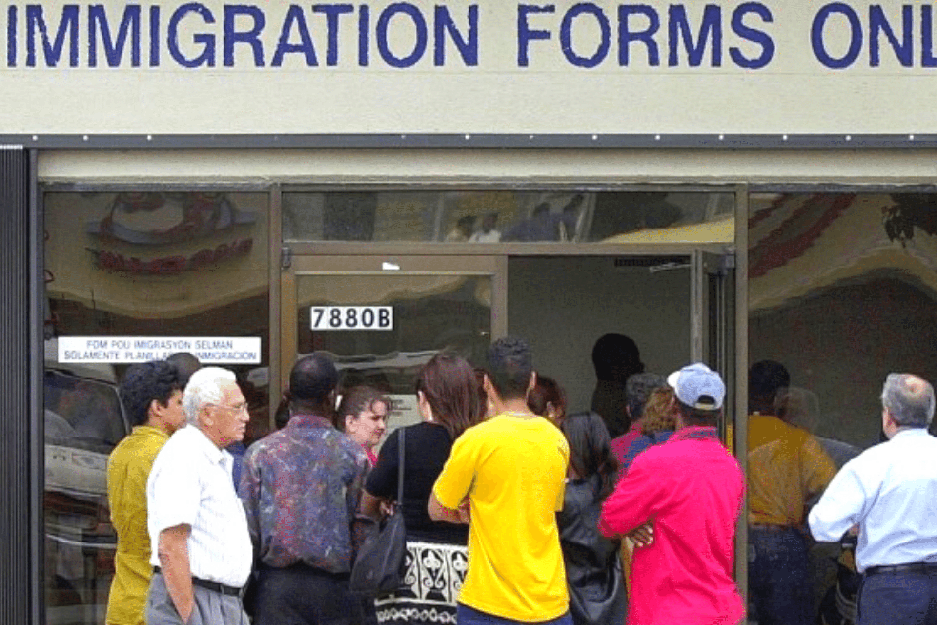People standing outside a building with a large sign stating, "Immigration Forms Only".