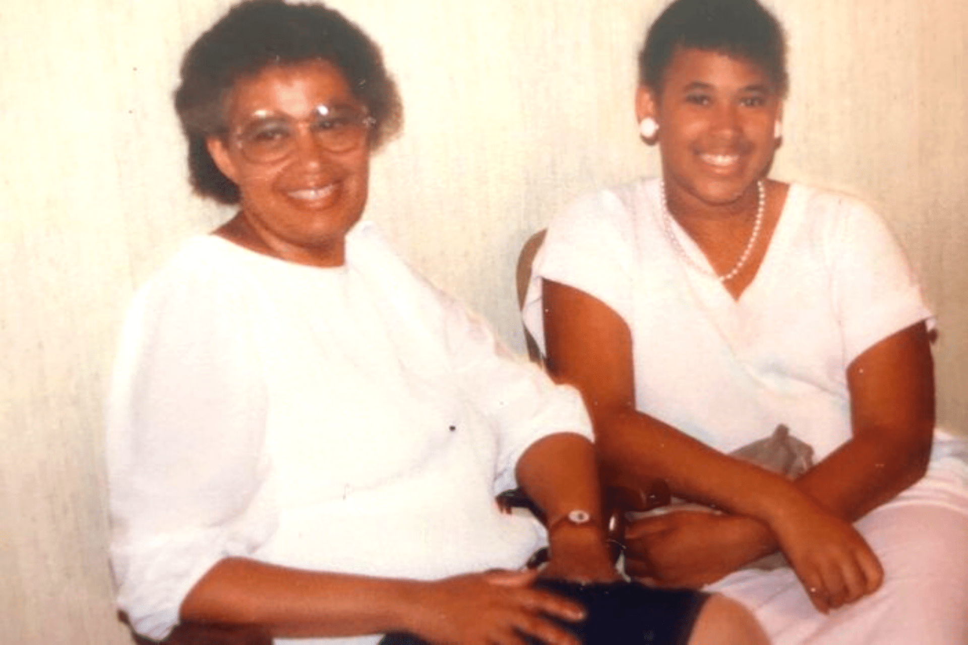 An old picture of a young woman and an older woman who's wearing eye glasses.