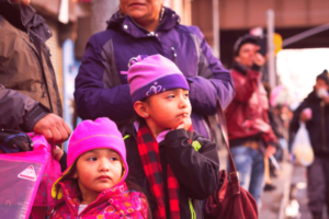 Children outside with adults in an urban setting wearing winter clothes