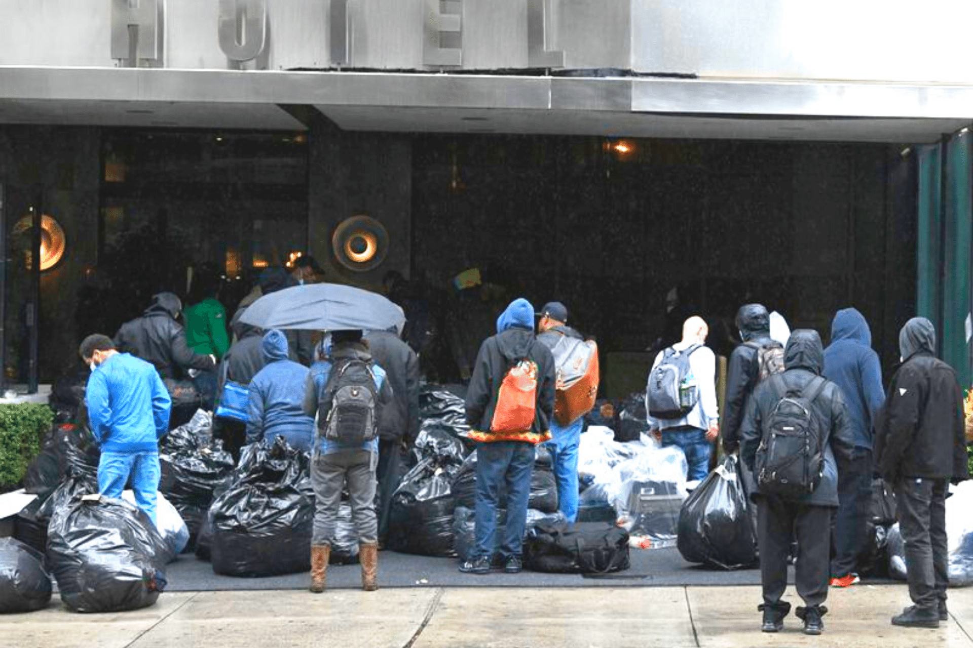 Image of a group of people with garbage bags outside a hotel.
