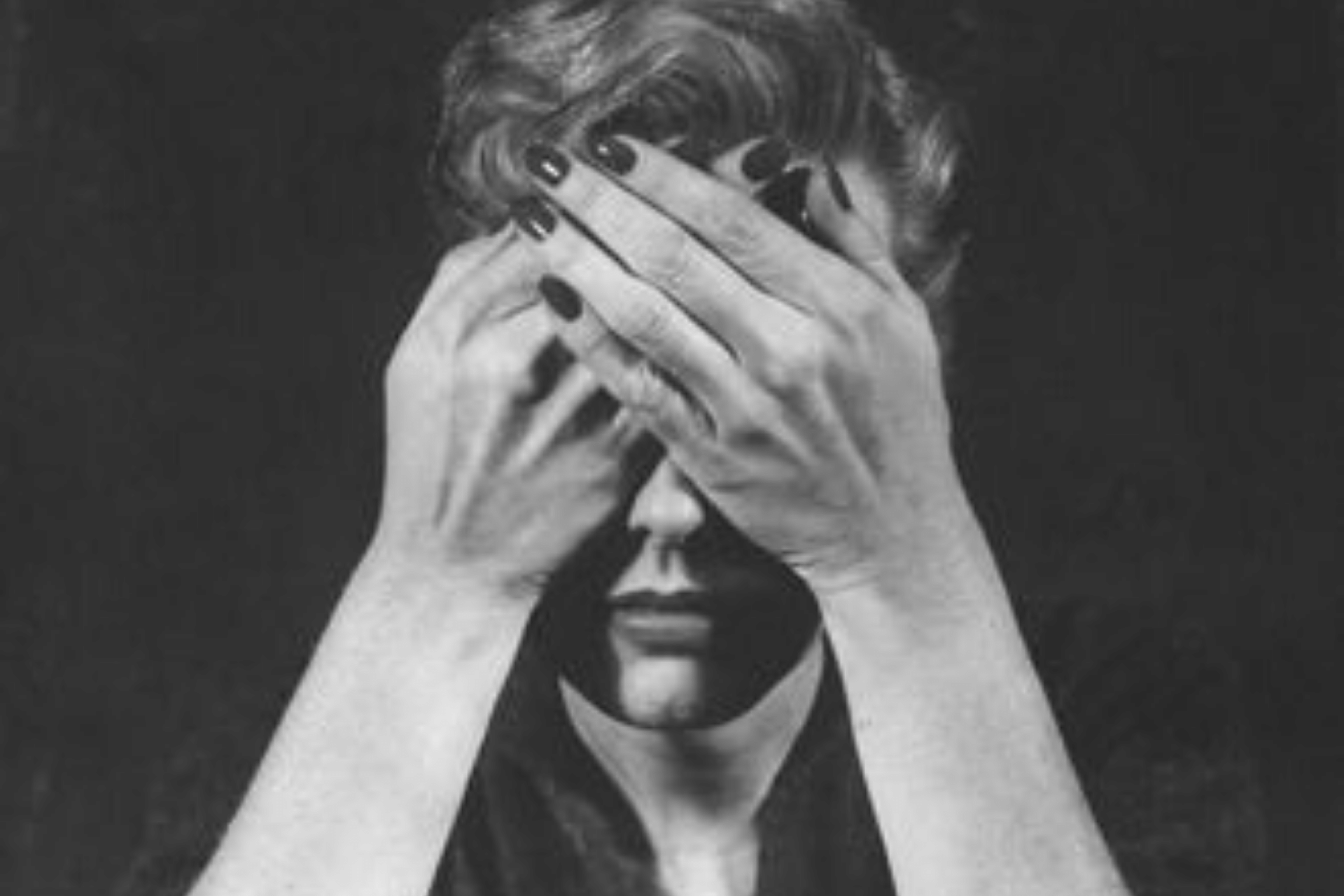 Woman with her hands over her eyes. She looks distressed.