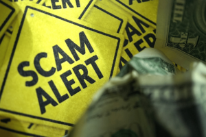 Yellow hazard sign with "scam alert" written on it.