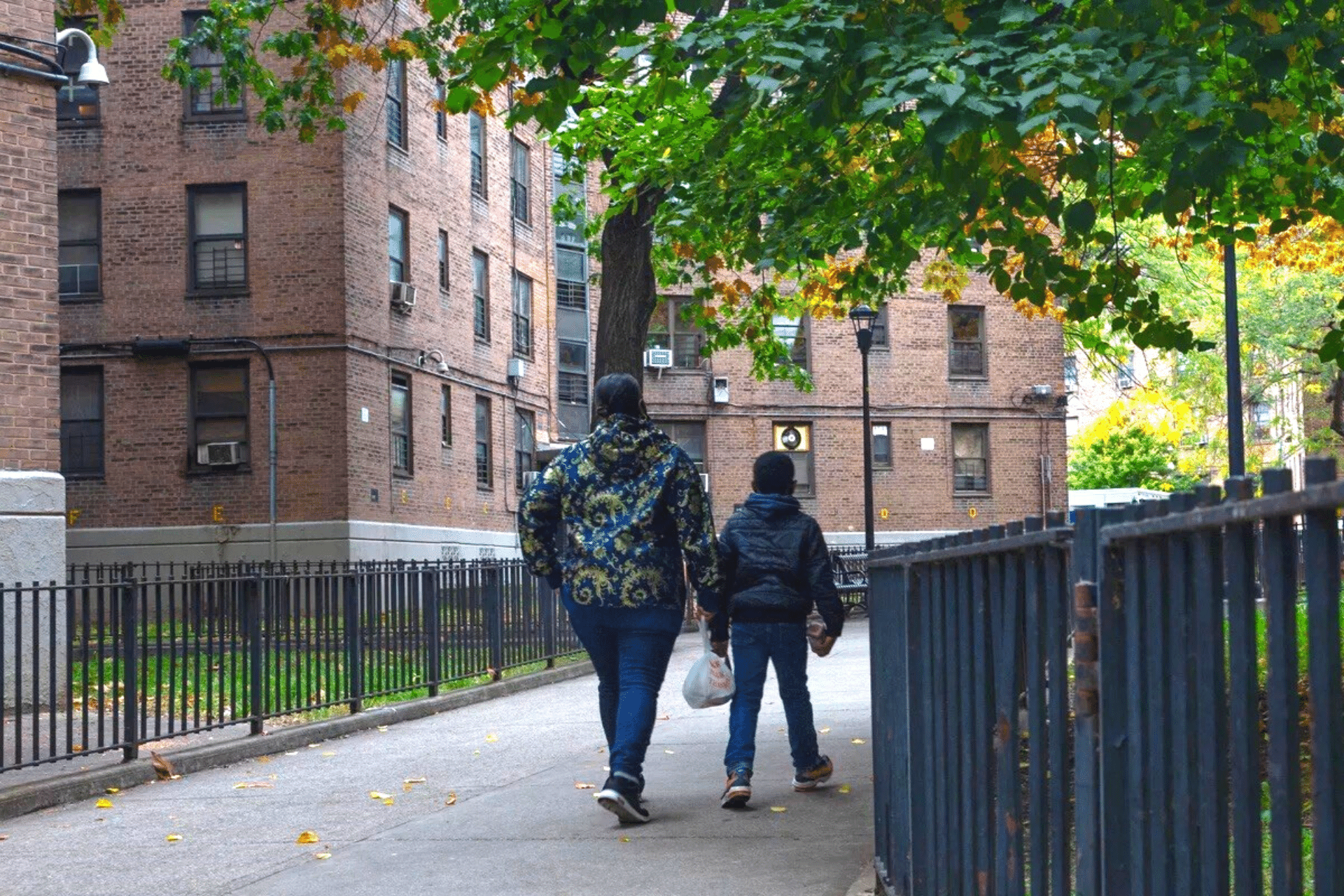 Two people walking through NYCHA housing outside