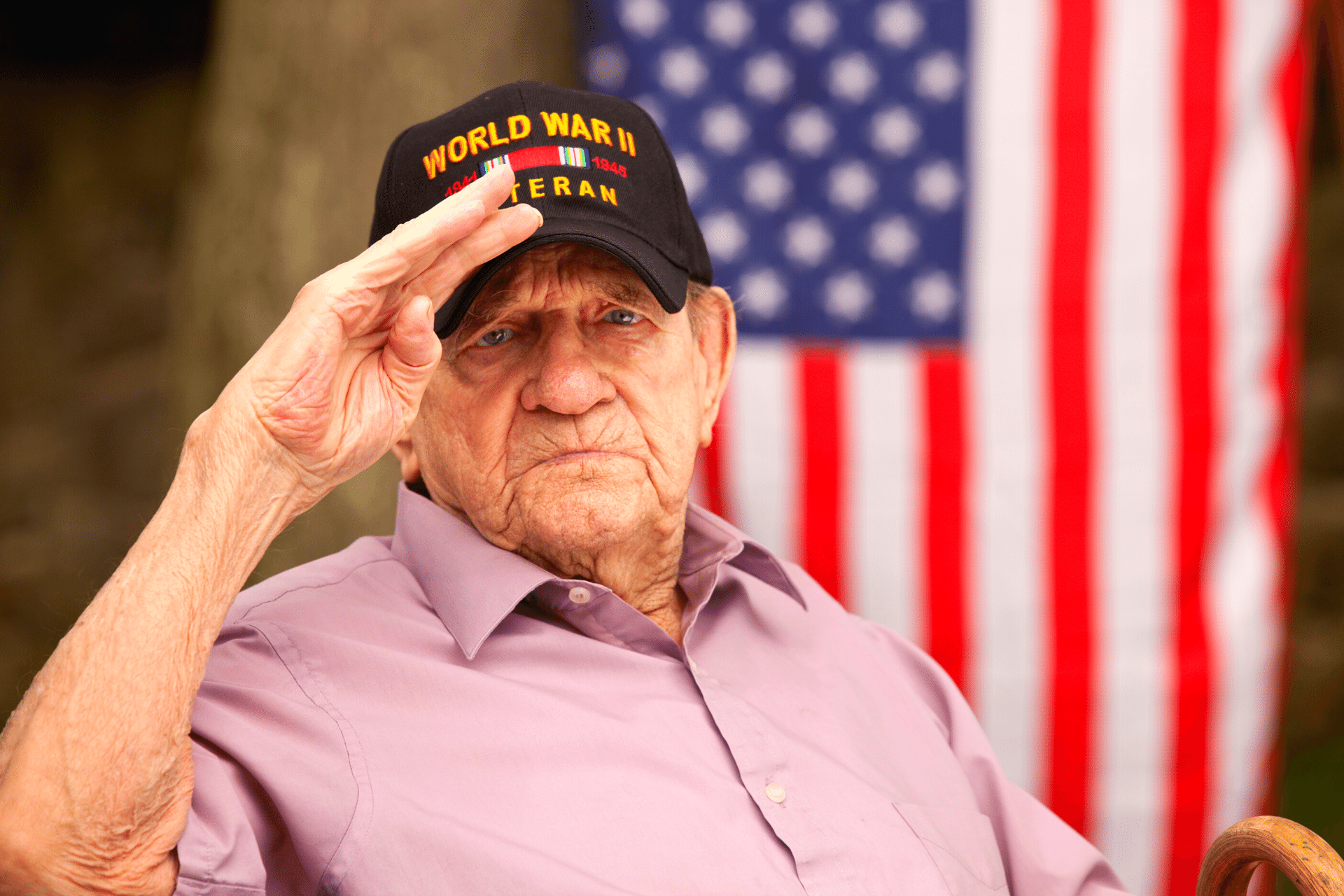 World War Two, Veteran wearing baseball cap with text, "World War Two Veteran". Saluting stock photo