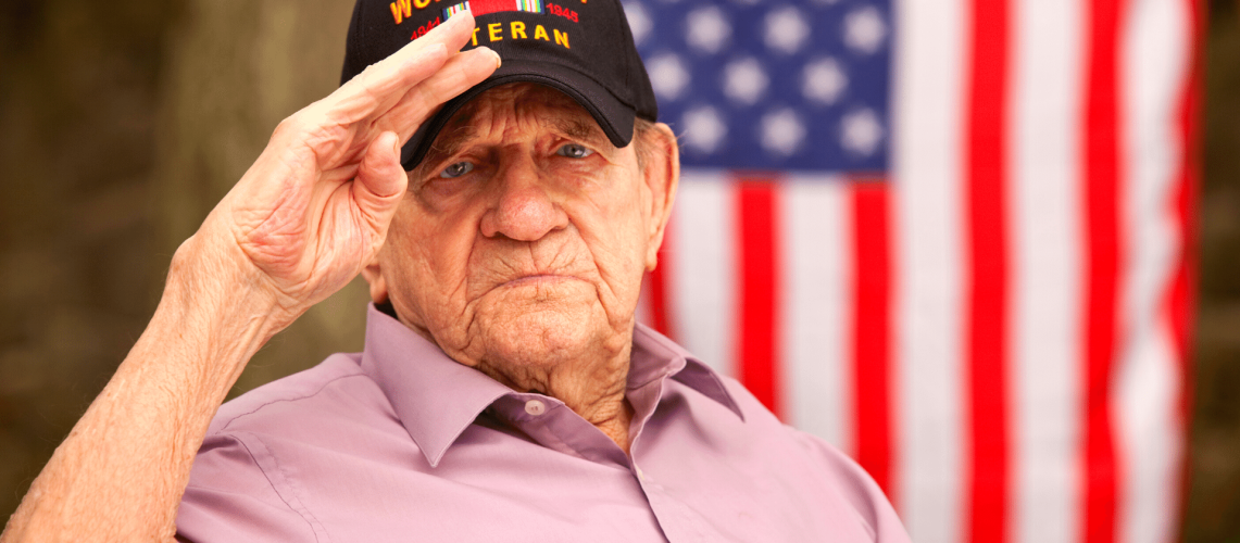 World War Two, Veteran wearing baseball cap with text, "World War Two Veteran". Saluting stock photo
