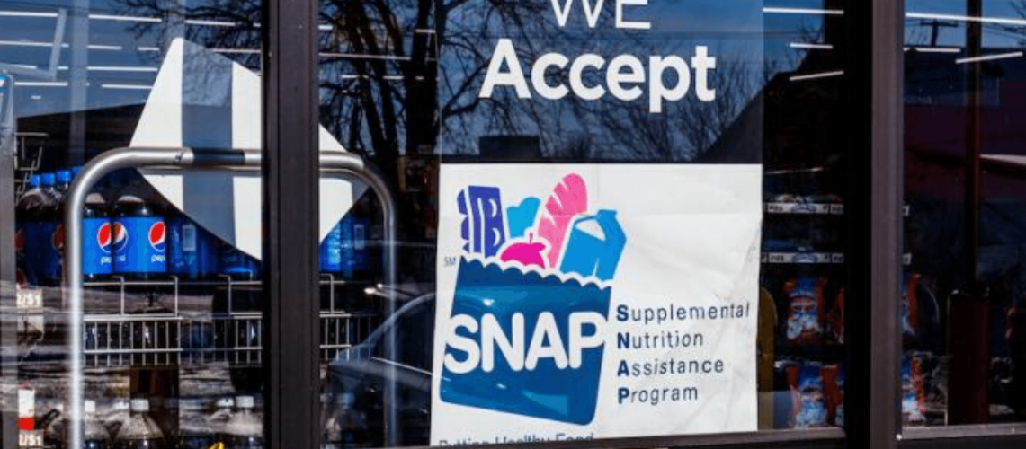 image of a grocery store window with a sign stating it accepts SNAP benefits.