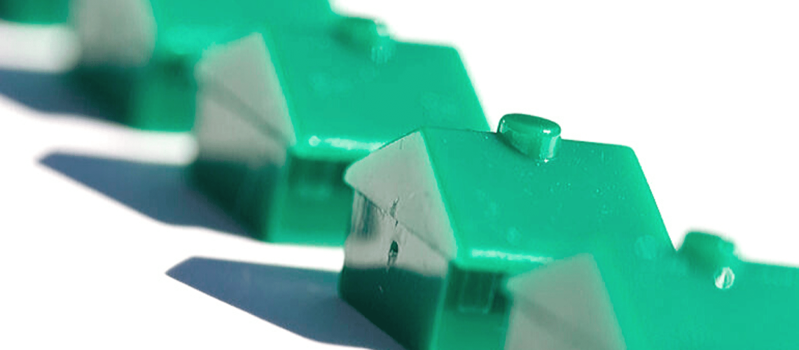 A row of three tiny green toy houses.