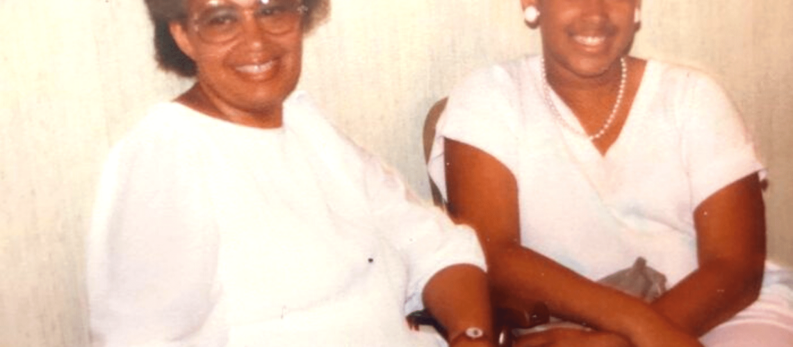 An old picture of a young woman and an older woman who's wearing eye glasses.