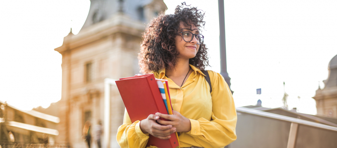 Young Adult Holding Books on College Campus