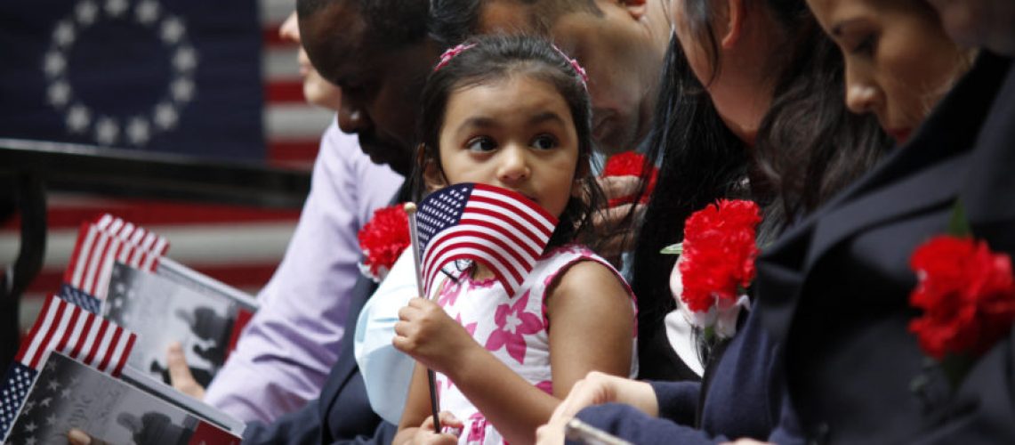 Philadelphia, PA, USA - June 14, 2019: The daughter of a immigrant holds an American flag while she joins her mother's naturalization ceremony on Flag Day at the historic Betsy Ross House in Philadelphia, Pennsylvania."n"n